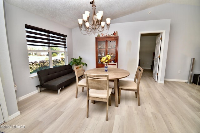 dining area with lofted ceiling, a notable chandelier, a textured ceiling, and light wood-type flooring