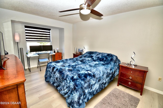 bedroom with ceiling fan, light hardwood / wood-style floors, and a textured ceiling