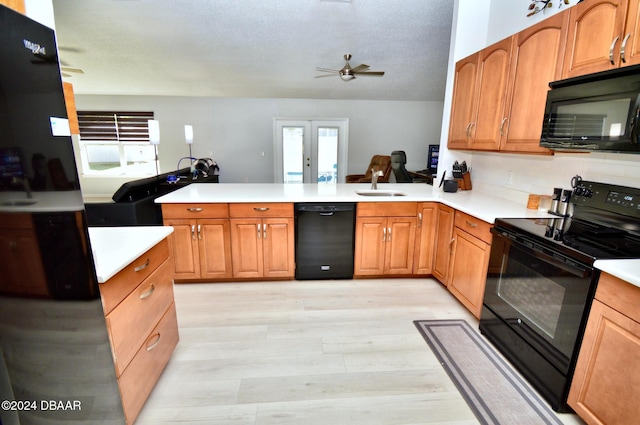 kitchen featuring sink, light hardwood / wood-style floors, black appliances, french doors, and kitchen peninsula