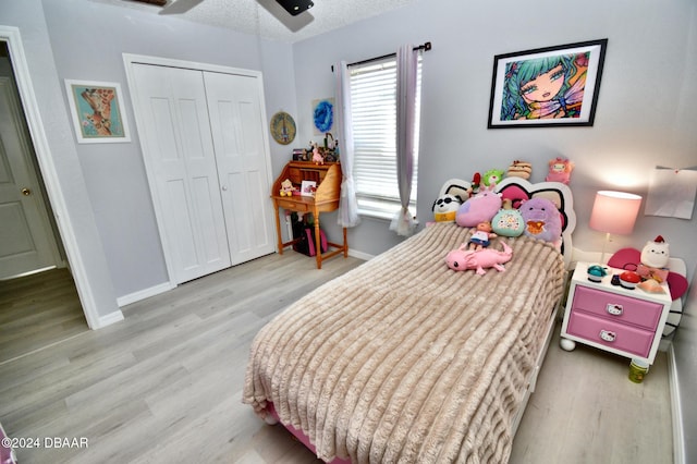 bedroom featuring ceiling fan, light hardwood / wood-style flooring, a closet, and a textured ceiling