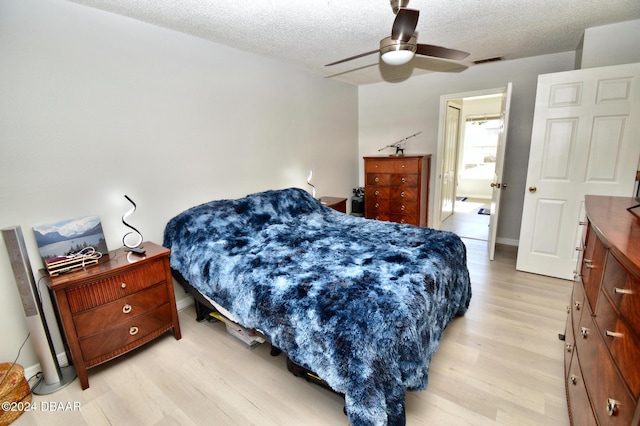 bedroom featuring ceiling fan, a textured ceiling, and light wood-type flooring