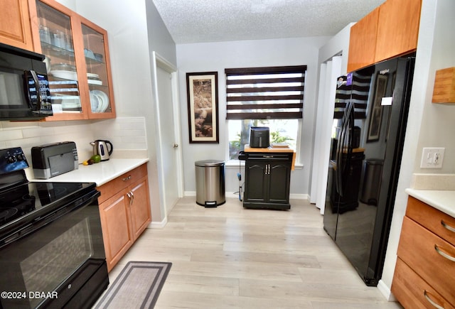 kitchen featuring tasteful backsplash, light hardwood / wood-style flooring, a textured ceiling, and black appliances