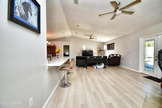 home office featuring ceiling fan, lofted ceiling, a textured ceiling, and light hardwood / wood-style floors