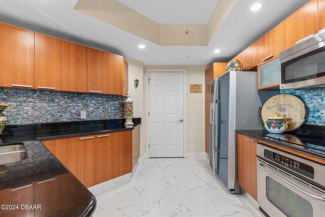 231 Riverside Dr Unit 1803-1, Daytona Beach, FL 32117 - kitchen with appliances with stainless steel finishes, brown cabinets, a tray ceiling, recessed lighting, and light marble finish flooring