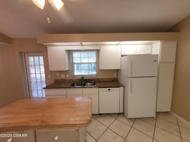 kitchen featuring light tile patterned floors, white appliances, a sink, white cabinets, and plenty of natural light