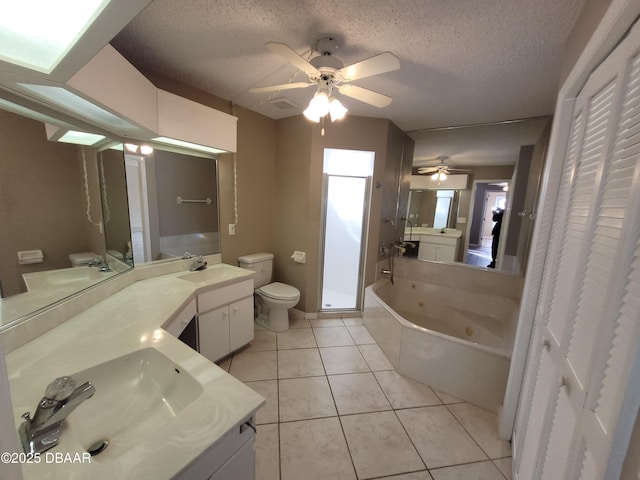 full bath featuring toilet, a sink, a textured ceiling, tile patterned flooring, and a whirlpool tub