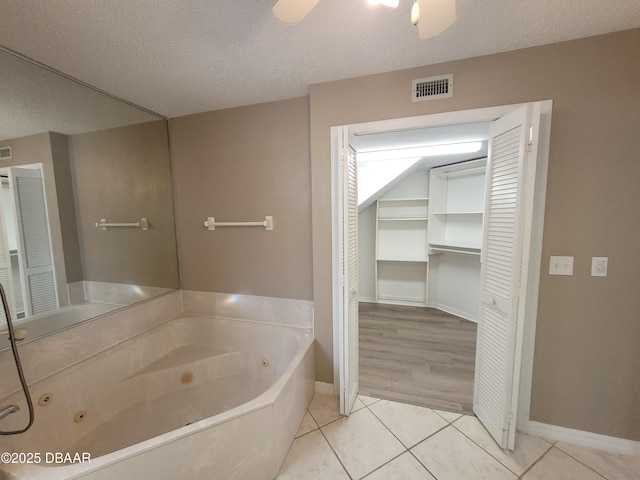 bathroom featuring a ceiling fan, visible vents, a tub with jets, and tile patterned floors