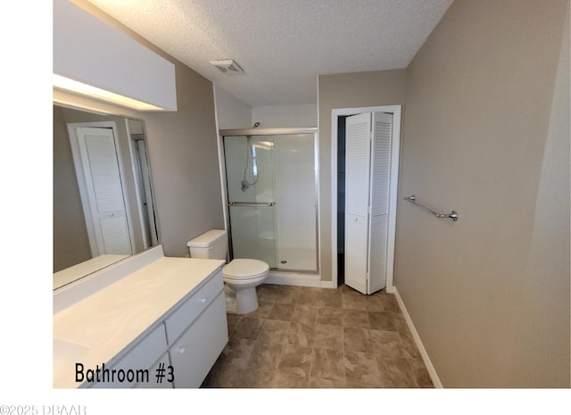 bathroom with a closet, toilet, a stall shower, vanity, and a textured ceiling