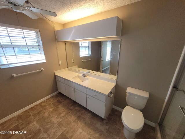 bathroom featuring baseboards, toilet, ceiling fan, a textured ceiling, and vanity