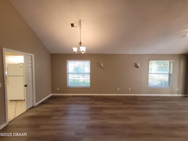 unfurnished dining area featuring baseboards, wood finished floors, vaulted ceiling, a textured ceiling, and a chandelier