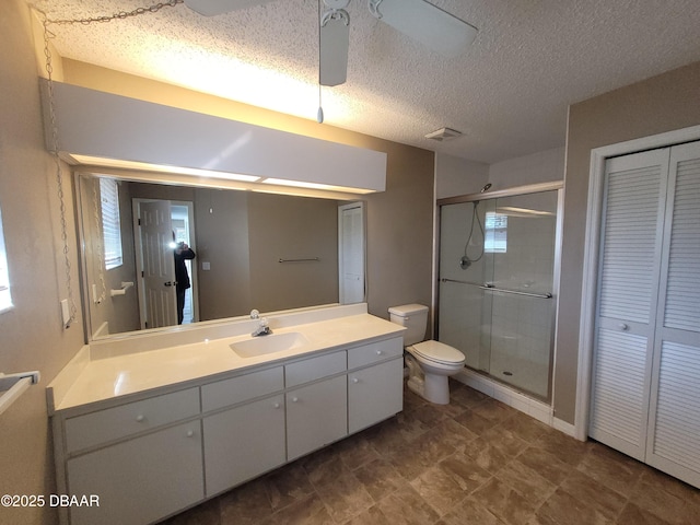 bathroom with ceiling fan, a textured ceiling, toilet, vanity, and a stall shower