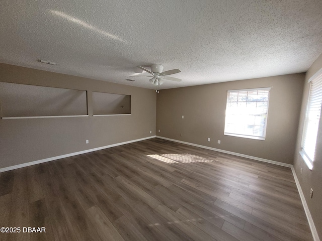 spare room featuring ceiling fan, a textured ceiling, dark wood-style flooring, visible vents, and baseboards