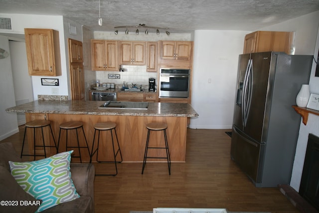 kitchen featuring appliances with stainless steel finishes, dark wood-type flooring, a breakfast bar area, and sink