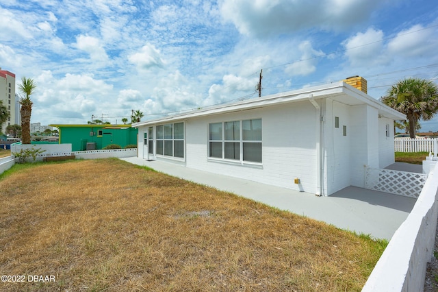 rear view of house with a patio and a lawn