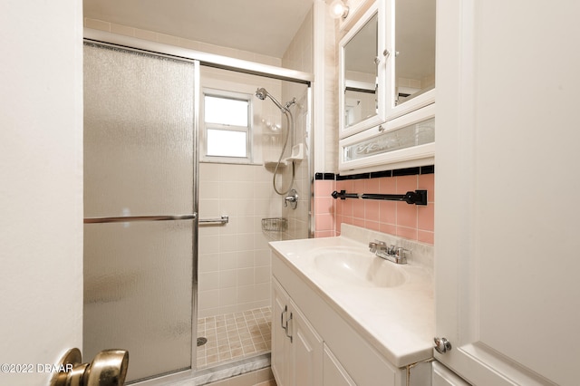 bathroom with vanity, tile walls, decorative backsplash, and a shower with door