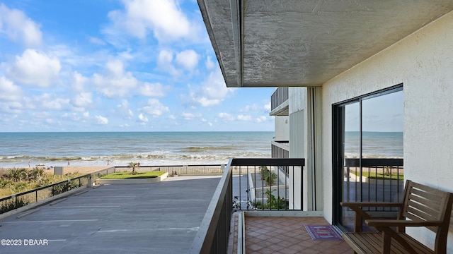 balcony with a water view and a view of the beach