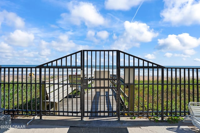 view of gate with a water view and a view of the beach