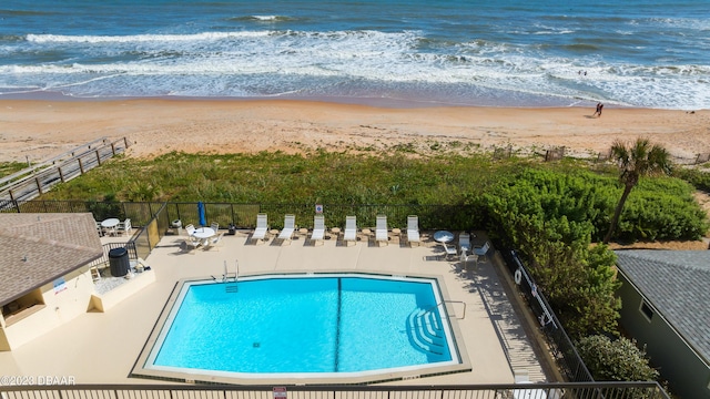 view of pool featuring a water view, a patio, and a beach view