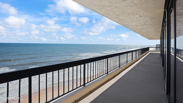 balcony featuring a view of the beach and a water view