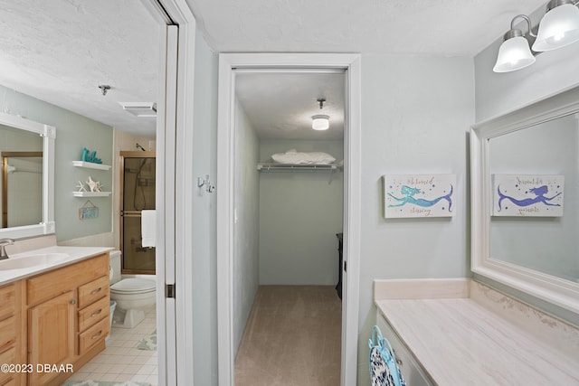 bathroom with tile patterned flooring, a textured ceiling, vanity, and toilet