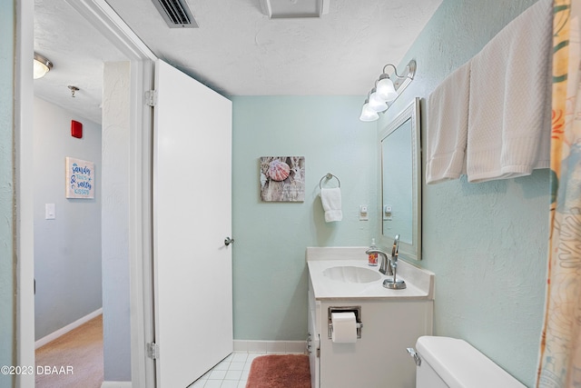 bathroom with toilet, a textured ceiling, vanity, and tile patterned floors