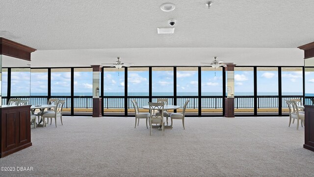 interior space featuring a textured ceiling, ceiling fan, a water view, and light carpet