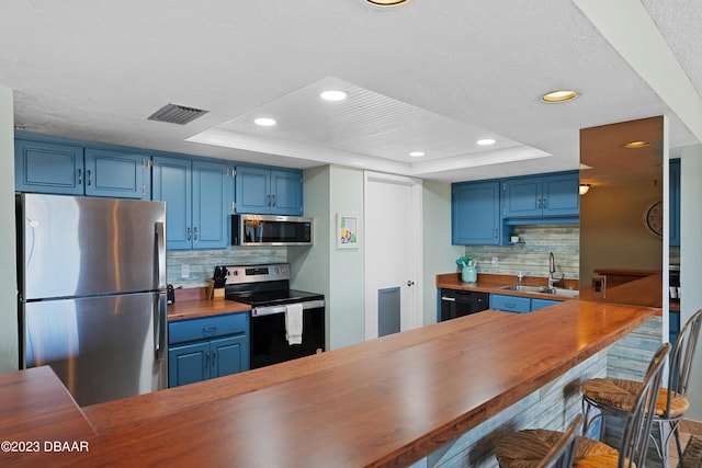 kitchen with blue cabinetry, appliances with stainless steel finishes, and a tray ceiling