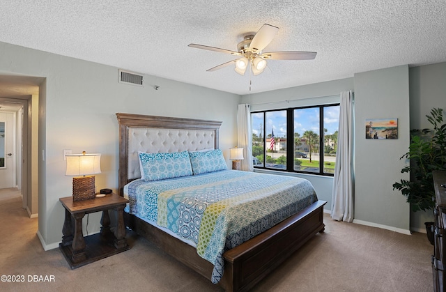 bedroom featuring ceiling fan, light colored carpet, and a textured ceiling