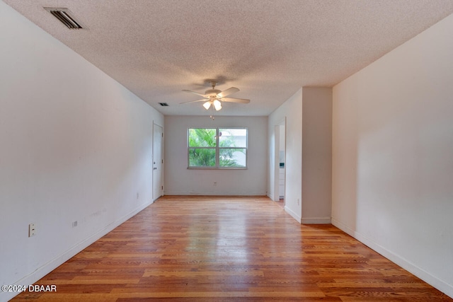 empty room with ceiling fan, light hardwood / wood-style floors, and a textured ceiling