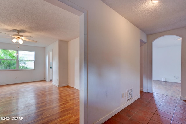 empty room with ceiling fan, hardwood / wood-style floors, and a textured ceiling