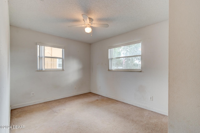 carpeted spare room with a textured ceiling, plenty of natural light, and ceiling fan