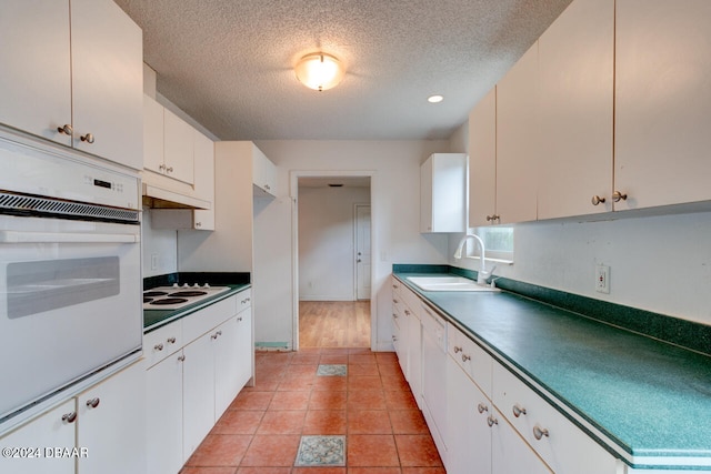 kitchen with sink, white appliances, a textured ceiling, and white cabinets