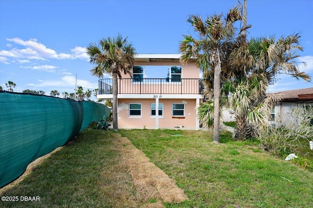 rear view of property with a balcony and a lawn