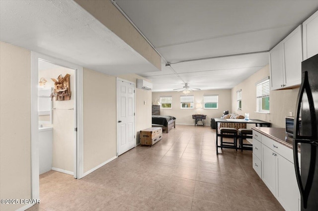 kitchen with white cabinetry, plenty of natural light, black refrigerator, and a wall mounted AC