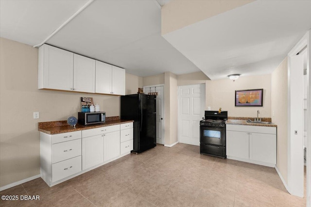 kitchen with white cabinetry, dark stone countertops, sink, and black appliances