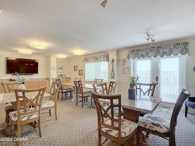 carpeted dining space featuring a textured ceiling and ornamental molding