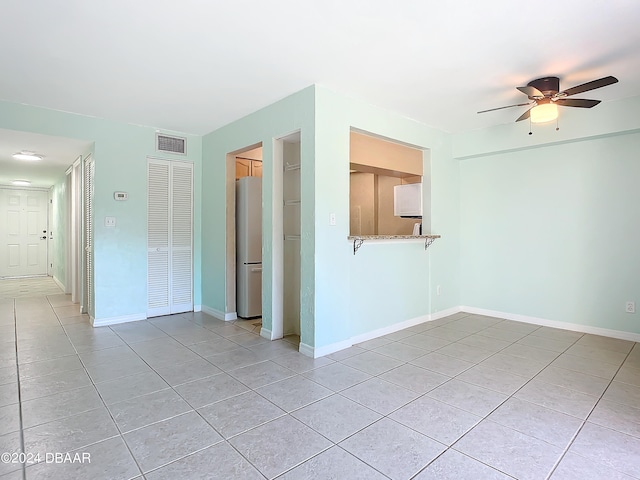 unfurnished room with light tile patterned floors and ceiling fan