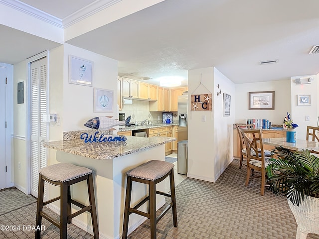 kitchen with kitchen peninsula, a breakfast bar area, sink, ornamental molding, and light brown cabinets