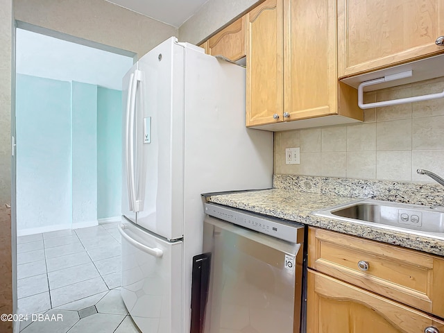 kitchen featuring decorative backsplash, light tile patterned floors, sink, stainless steel dishwasher, and light brown cabinetry