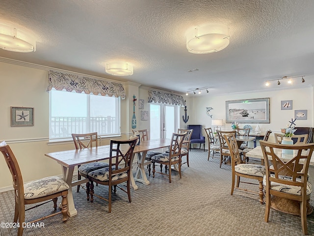 dining room featuring ornamental molding, a textured ceiling, carpet floors, and rail lighting