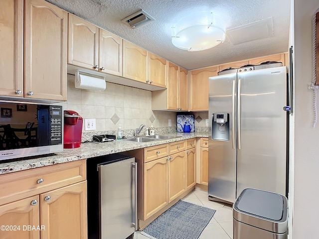 kitchen with light brown cabinets, stainless steel appliances, and light tile patterned flooring