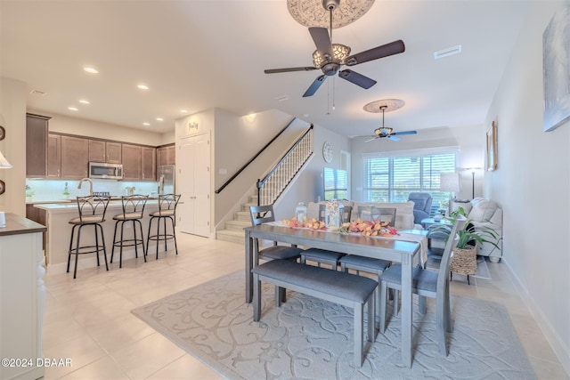 dining space with sink, light tile patterned floors, and ceiling fan