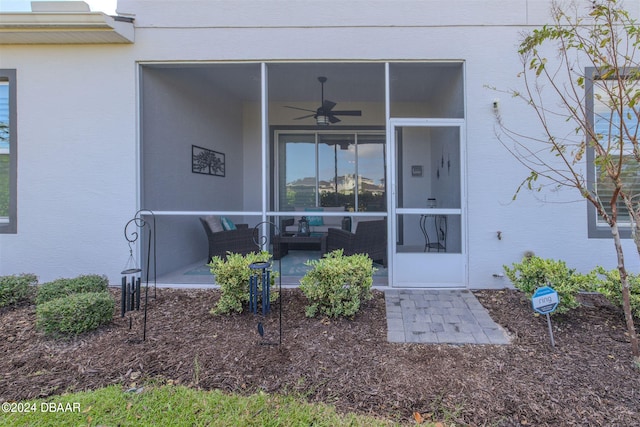 view of exterior entry featuring ceiling fan, a patio, and an outdoor living space