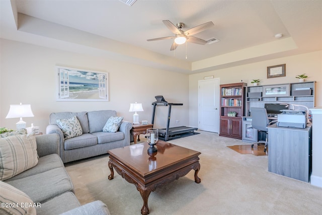 living room with light carpet, ceiling fan, and a tray ceiling