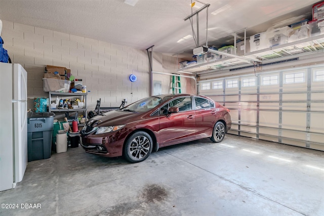 garage featuring a garage door opener and white refrigerator