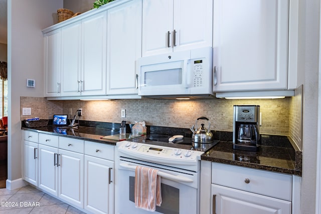 kitchen with dark stone counters, light tile patterned floors, white appliances, white cabinets, and decorative backsplash