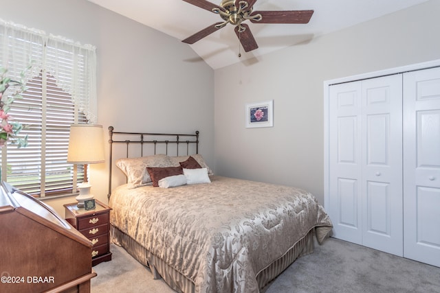 bedroom with ceiling fan, light carpet, a closet, and vaulted ceiling