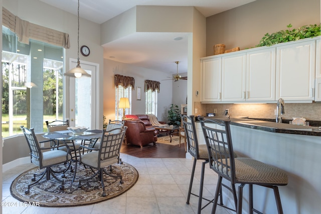 dining space with light wood-type flooring, sink, ceiling fan, and a towering ceiling