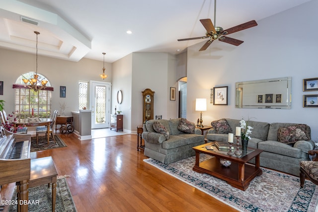 living room featuring a towering ceiling, hardwood / wood-style flooring, and ceiling fan with notable chandelier