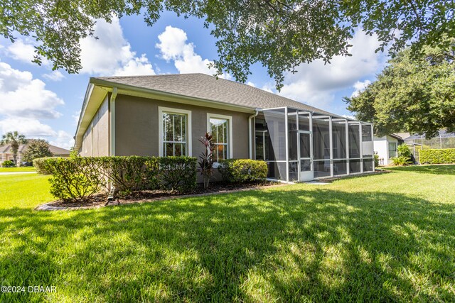 rear view of property with a lanai and a yard